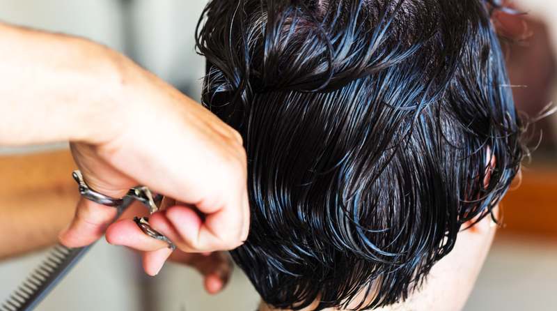 Man styling short textured hair with a matte pomade in natural lighting